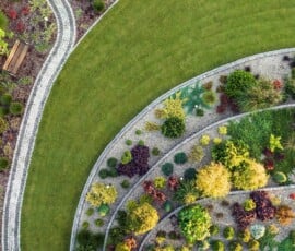 Aerial view of a landscaped garden with curved grass paths, tiered flower beds, stone steps, and a wooden bench in the corner—perfect inspiration for your homepage's welcoming aesthetic. Aerial view of a landscaped garden with curved grass paths, tiered flower beds, stone steps, and a wooden bench in the corner—perfect inspiration for your homepage's welcoming aesthetic.